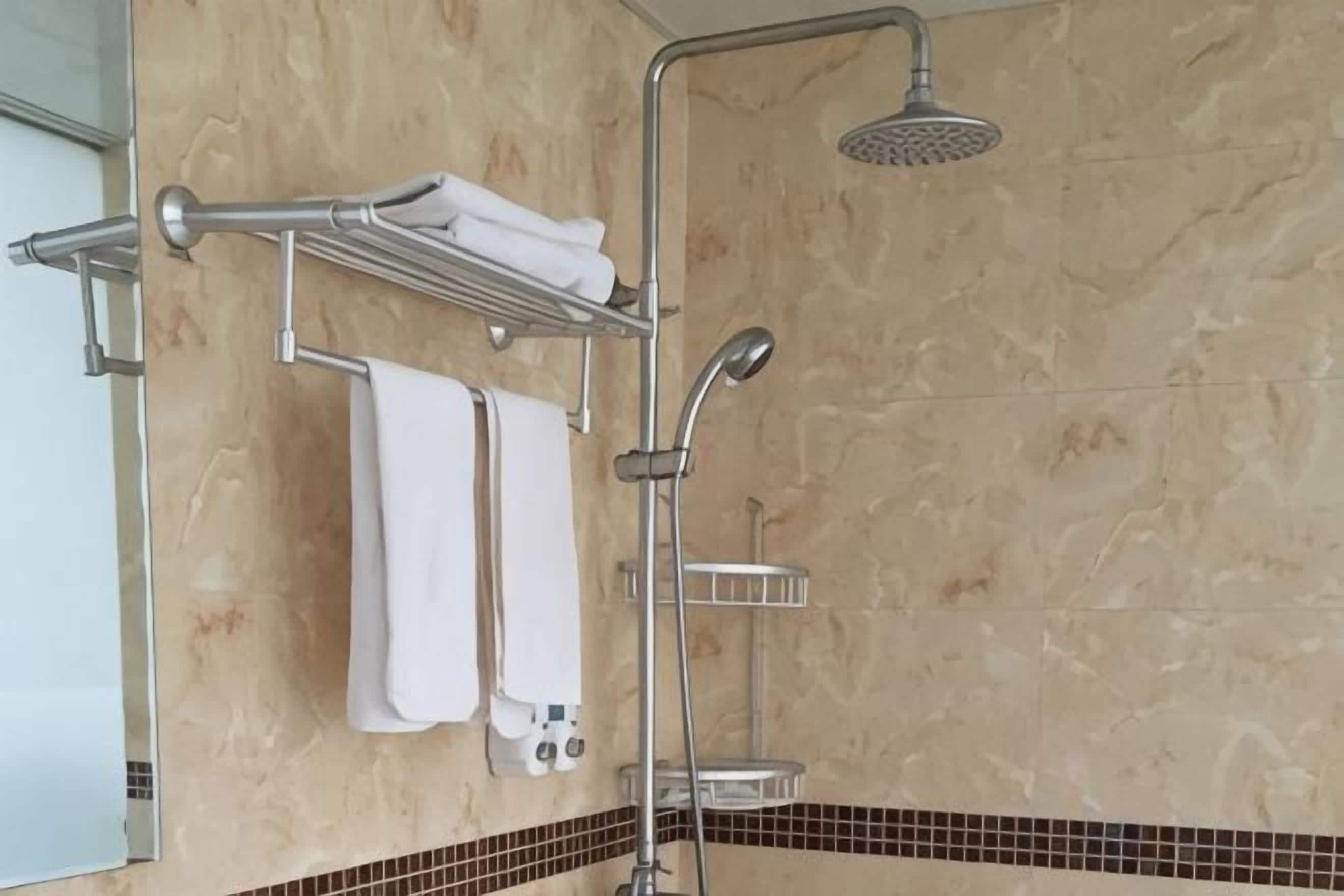 A bathroom with a shower, towel rack, and a tiled floor.