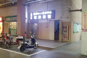 A building entrance with a sign, a scooter parked outside, and a poster on the wall. - Jinshang Hostel (Shanghai)