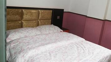 A bed with a headboard, a nightstand, and a wall with a decorative panel.