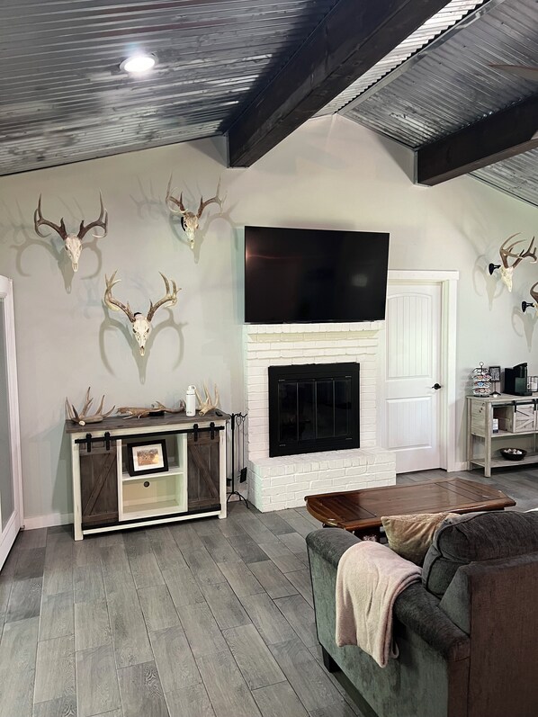 A living room with a fireplace, mounted deer skulls, a TV, and a rustic wooden coffee table.