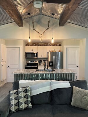 A modern kitchen with a central island, stainless steel appliances, and a ceiling with antler decorations.