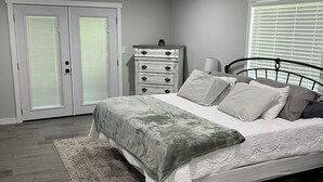Ein Schlafzimmer mit Bett, Kommode, Deckenventilator und Fenster mit Jalousien.