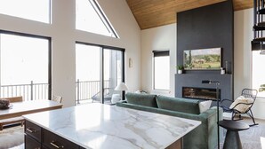 A spacious living area with a large window, a fireplace, and a modern kitchen island.