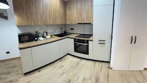 A modern kitchen with wooden cabinets, a microwave, a sink, and a stove.