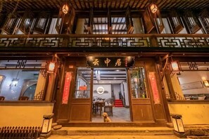 A traditional building with a wooden facade, a staircase leading to the entrance, and a dog visible outside.