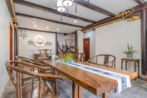 A dining area with a long wooden table, chairs, and a hanging light fixture.