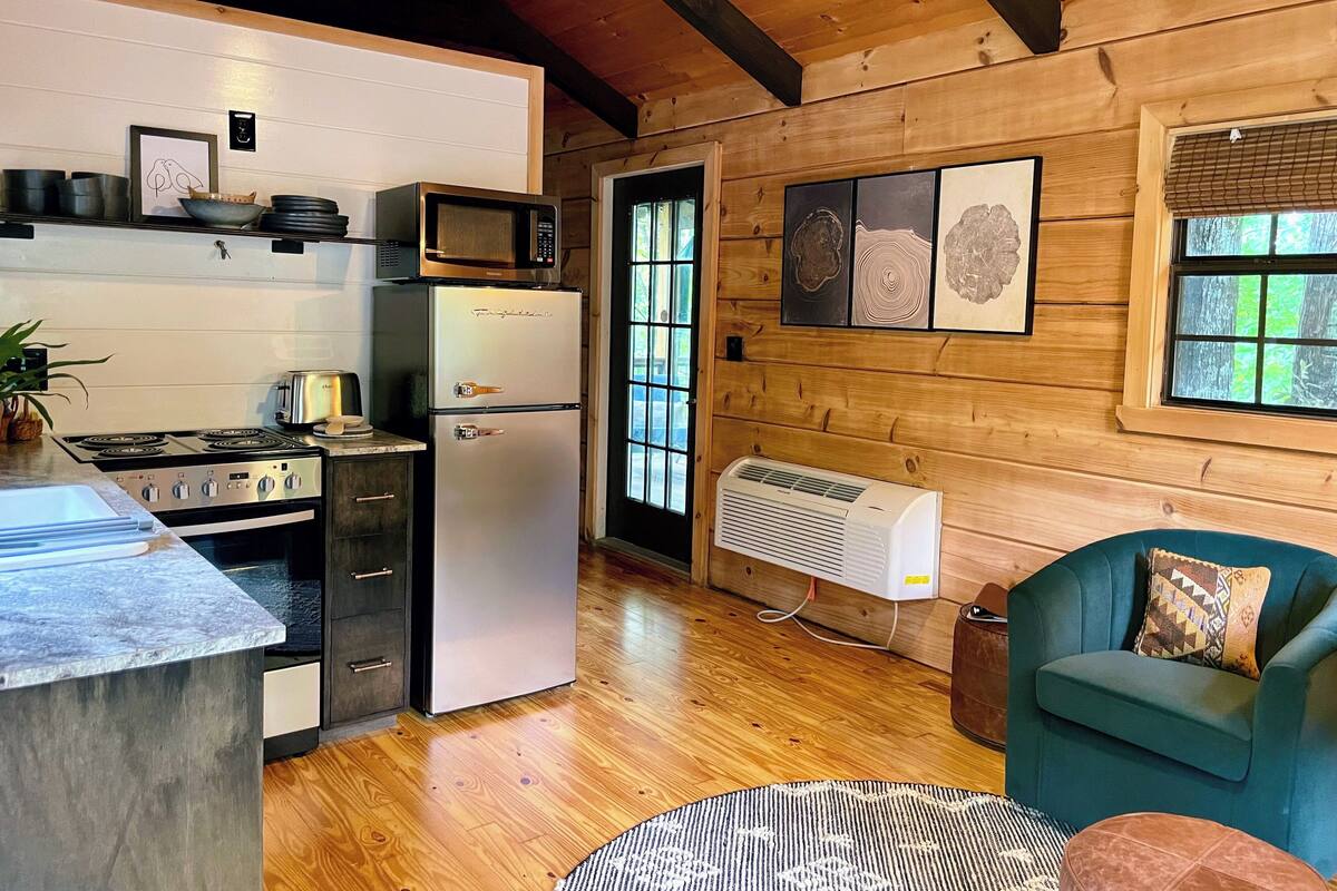 A compact kitchen with a refrigerator, stove, microwave, and a small dining area.