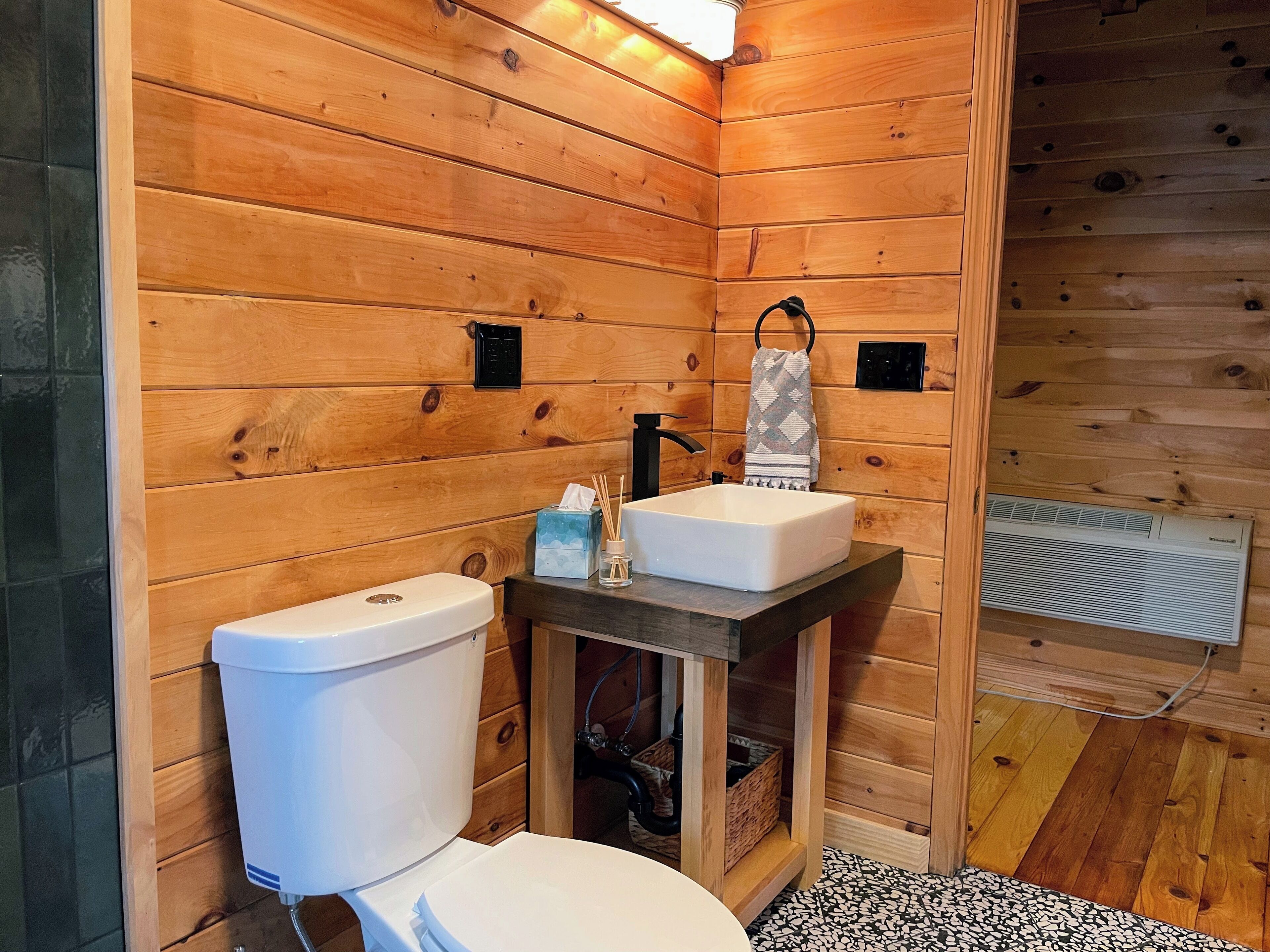 Ein Badezimmer einer Holzhütte mit Toilette, Waschbecken und Handtuchhalter.