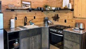 A modern kitchen with wooden walls, a stainless steel stove, and a built-in oven. - The Shaded Crest (Adults Only 21+) (Lake Lure)