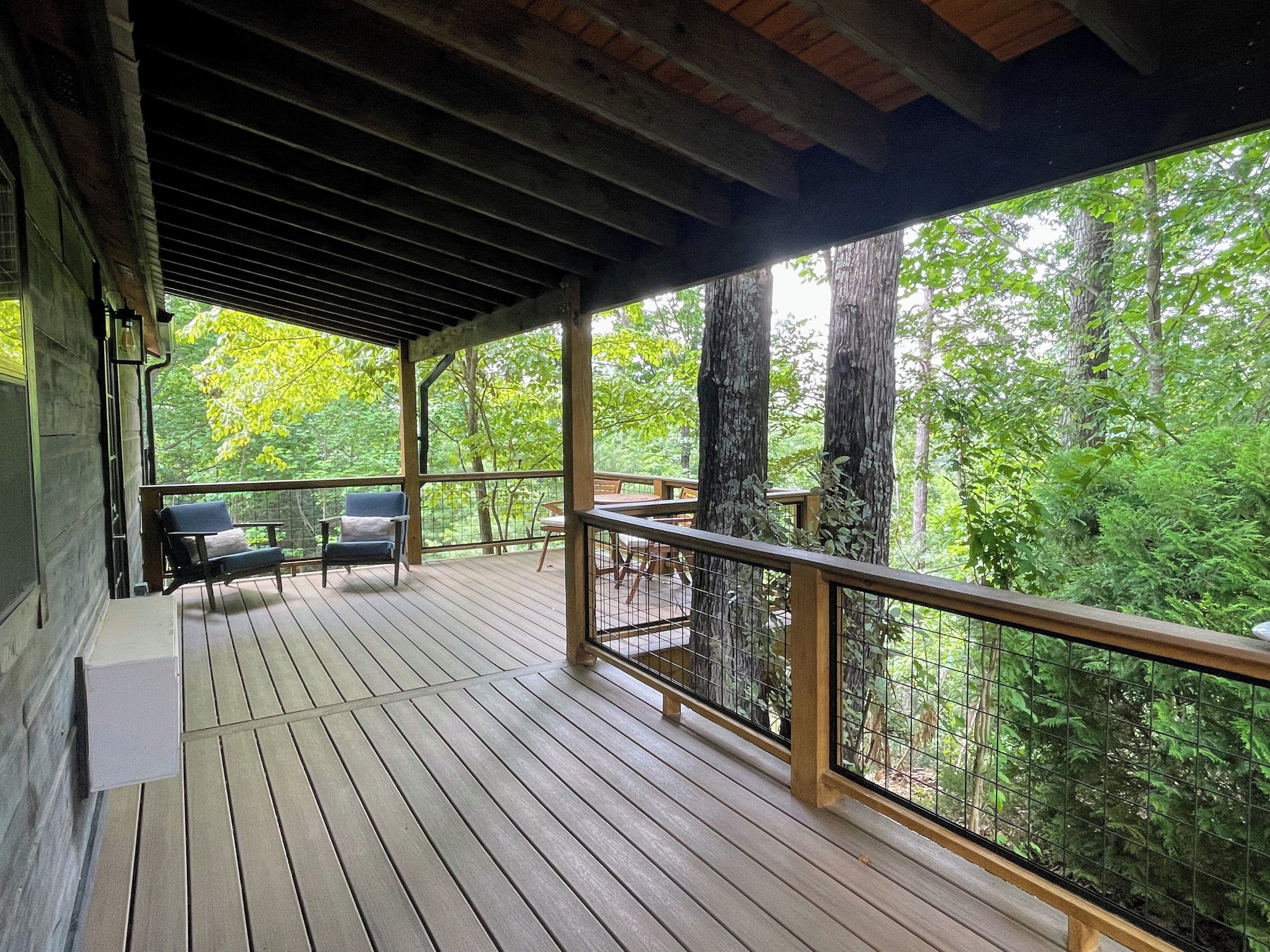 A wooden deck with a railing, overlooking a forested area.