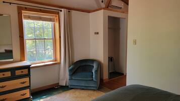Un dormitorio con cama, cómoda, ventana con cortinas y una silla.