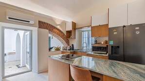 A modern kitchen with a marble countertop, wooden cabinetry, and a built-in island with bar stools.