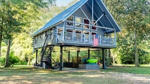 Eine Hütte mit Balkon, einer Treppe und einer überdachten Sitzgelegenheit.
