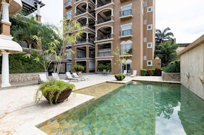 Relax by the pool surrounded by lush greenery and comfortable lounge chairs.