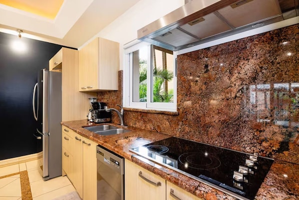Enjoy cooking in this kitchen with a sleek induction cooktop, refrigerator, and dishwasher.