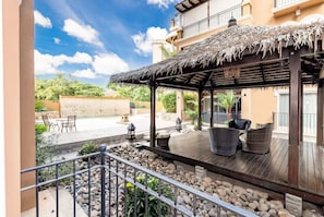 Relax in a shaded outdoor space with wicker chairs and a small table, perfect for dining or socializing.