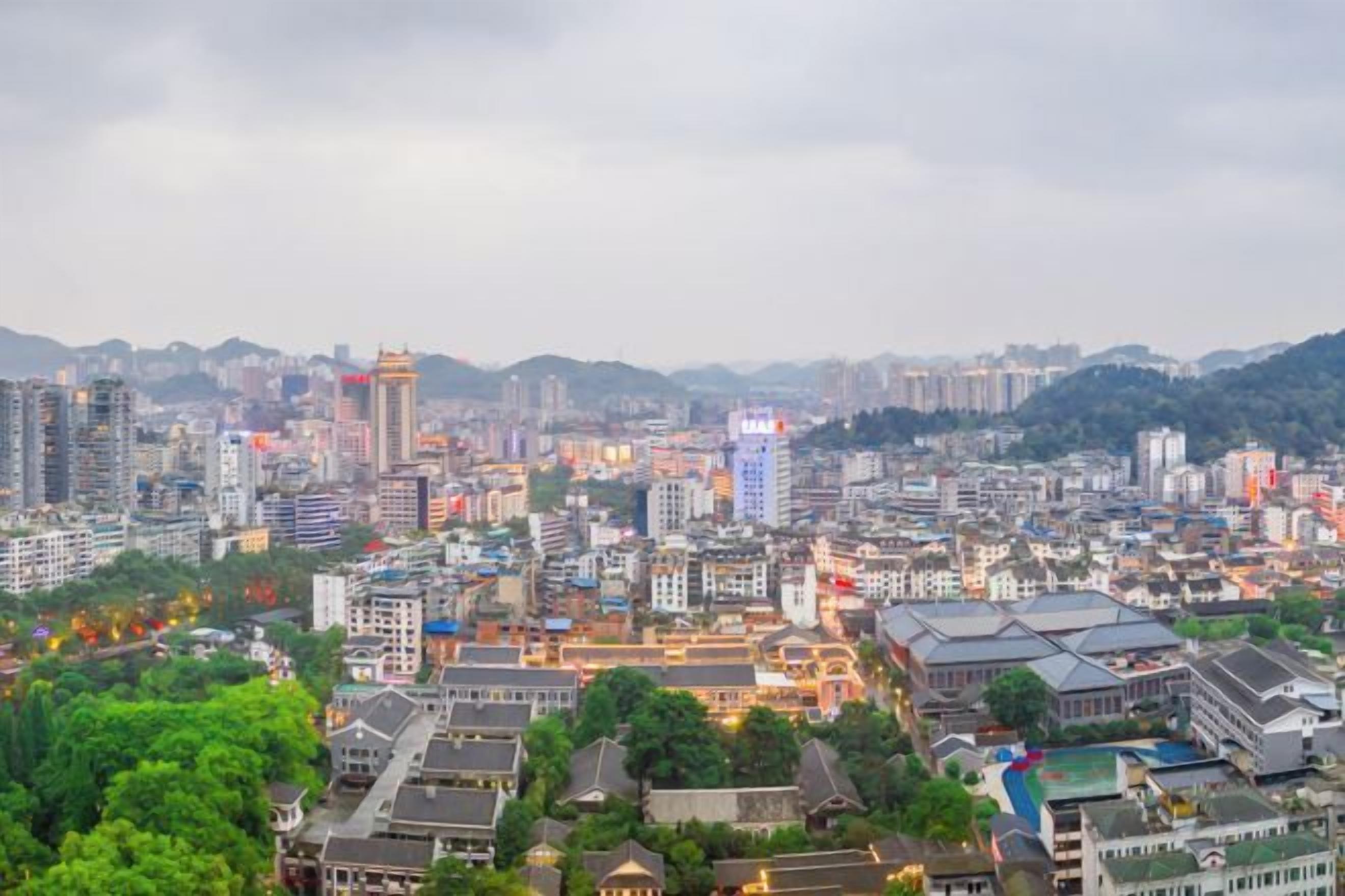 A cityscape with a mix of modern and traditional buildings, a prominent tower, and a view of the surrounding hills.