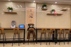 A seating area with a teddy bear, a coffee machine, and potted plants. - Tianmei Hotel (Zunyi club site) (Zunyi)