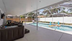 Ein überdachter Außenbereich mit Whirlpool, Pool und Liegestühlen.