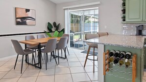 Eine moderne Küche mit Essbereich, einem Weinkühlschrank und einem großen Fenster.