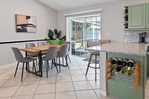 A modern kitchen with a dining area, a wine rack, and a large window. - Spacious 3BR Home in Prime Location – Private Heated Pool & Hot Tub (Sarasota)