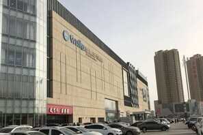 Un edificio grande con un letrero llamativo, varios espacios de estacionamiento y edificios altos a su alrededor.