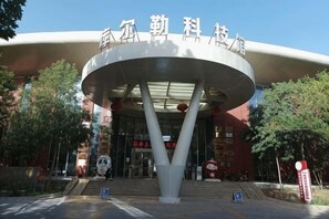 Un bâtiment moderne doté d’une structure d’entrée circulaire, d’une signalétique et surplombant un ciel dégagé.