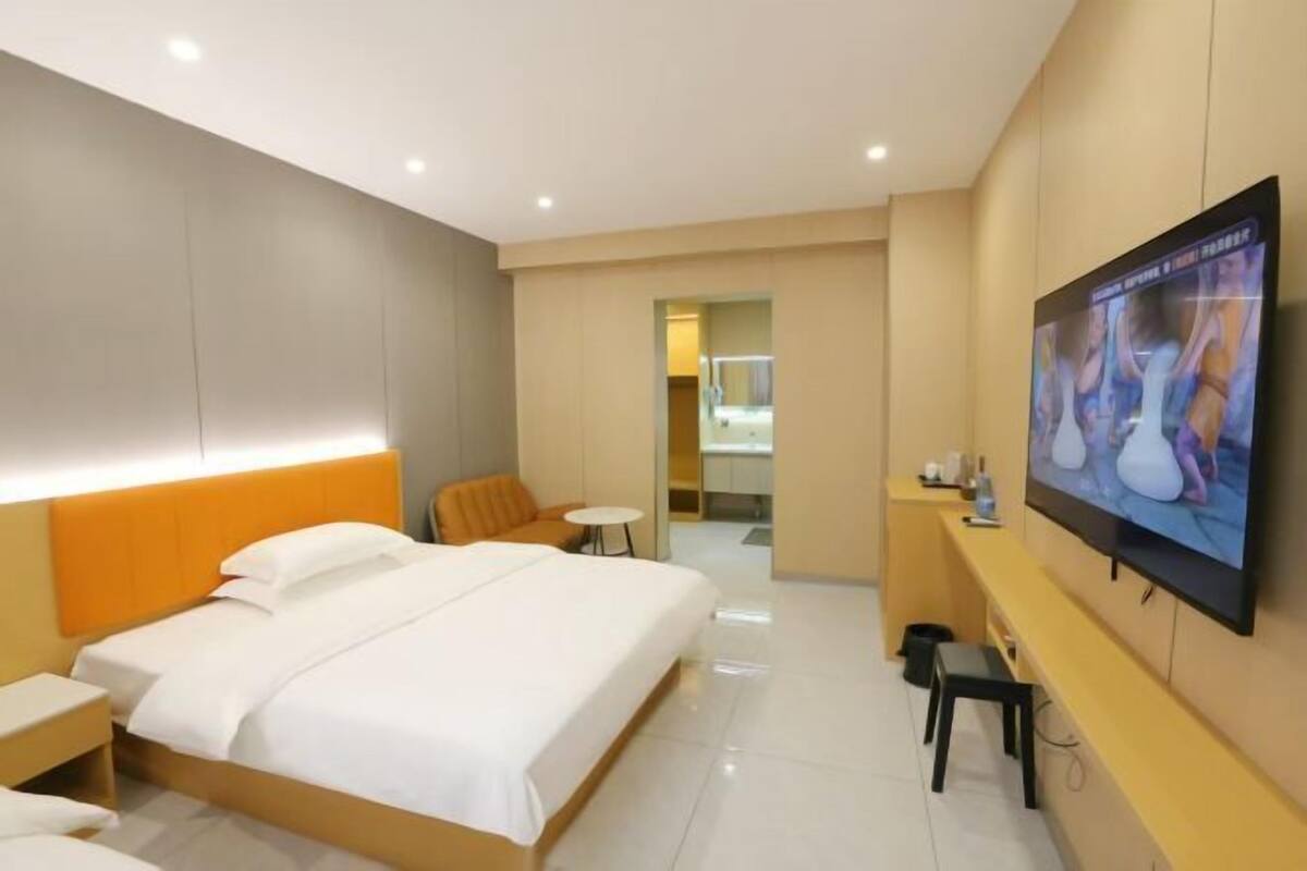 A hotel room with a bed, a TV, a small table, and a chair.