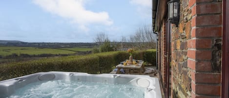 Relax in a serene outdoor setting with a hot tub and dining area surrounded by lush greenery.