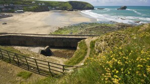 A coastal landscape with a beach, a bridge, and a cliff with houses. - *3 Bed Bungalow*Near Portreath Beach*Hot Tub*Free Parking & WiFi* (Redruth)