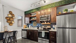 Una cocina moderna con armarios de madera oscura, electrodomésticos de acero inoxidable y una planta verde sobre la encimera.