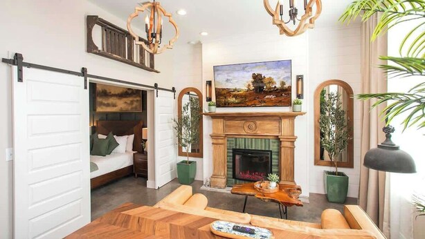 Un salon moderne avec une cheminée, un grand tableau et un coin repas comprenant une table et des chaises en bois.