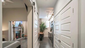 Un couloir étroit avec un lit sur le côté gauche, une cheminée et un coin repas comprenant une table et des chaises.