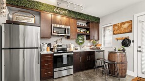 A modern kitchen with stainless steel appliances, dark wooden cabinets, and a green wall accent.