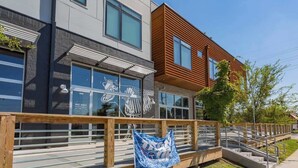 A modern building with a mix of grey and wooden facades, large windows, and a wooden staircase leading to a deck area. - Industrial Design Apt | 10 Min to Downtown (Nashville)