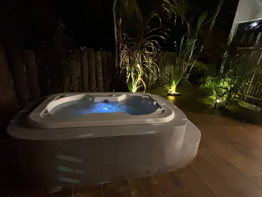 A hot tub in a garden area with tiled flooring and surrounding plants.