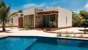Une maison moderne dotée d’une piscine, d’une façade en pierre et de grandes fenêtres.
