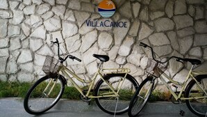 Deux vélos sont garés contre un mur de pierre, au-dessus duquel on peut voir un logo.