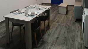 A dining area with a wooden table set for four, a ceiling fan, and a blue door. - Haraki Blue Houses (Rhodes)