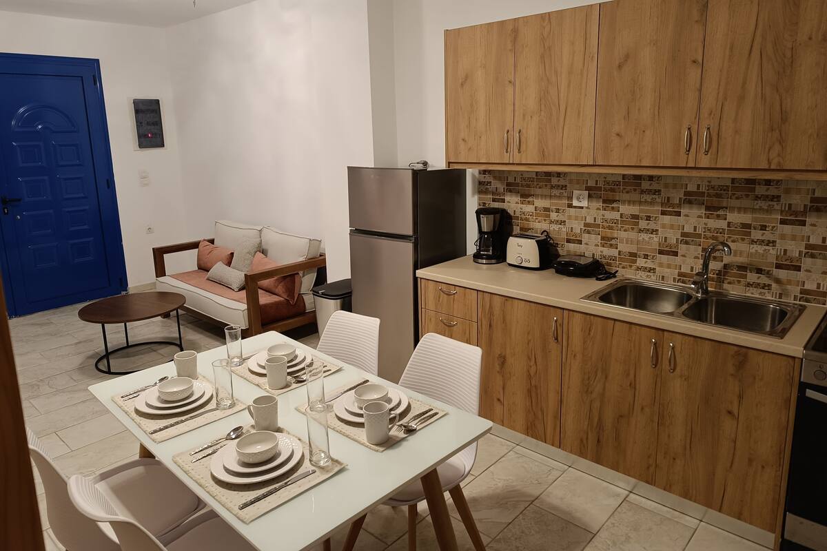 A compact kitchen with wooden cabinets, a refrigerator, a coffee maker, and a toaster.