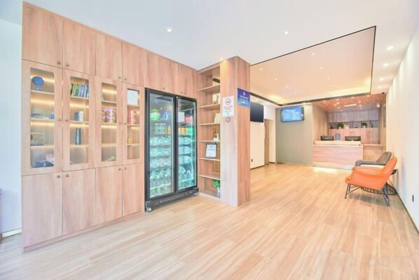 Un hall de hotel con mostrador de recepción de madera, una zona de estar y una máquina expendedora.
