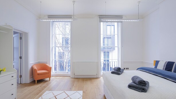 Une chambre à coucher moderne avec un lit, une chaise et une commode.