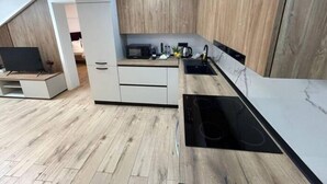 A modern kitchen with wooden cabinets, a built-in microwave, and a black stove.