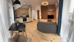 A modern living space with a dining area, a kitchen, and a seating area with a TV.