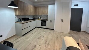 Een moderne keuken met houten kastjes, een zwart aanrecht en een eethoek met een tafel en stoelen.