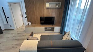 Een moderne woonkamer met een flatscreen televisie, inbouwplanken en een bank.
