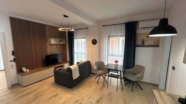 Een moderne woonkamer met een bank, een eettafel met stoelen, een televisie en een houten accentmuur.