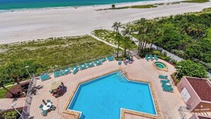 A resort with a swimming pool, lounge chairs, and a view of the beach.