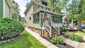 A two-story house with a front porch, a mailbox, and an American flag.