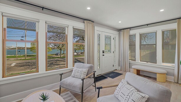 A modern living room with large windows, a bench, and a door with decorative glass panels.